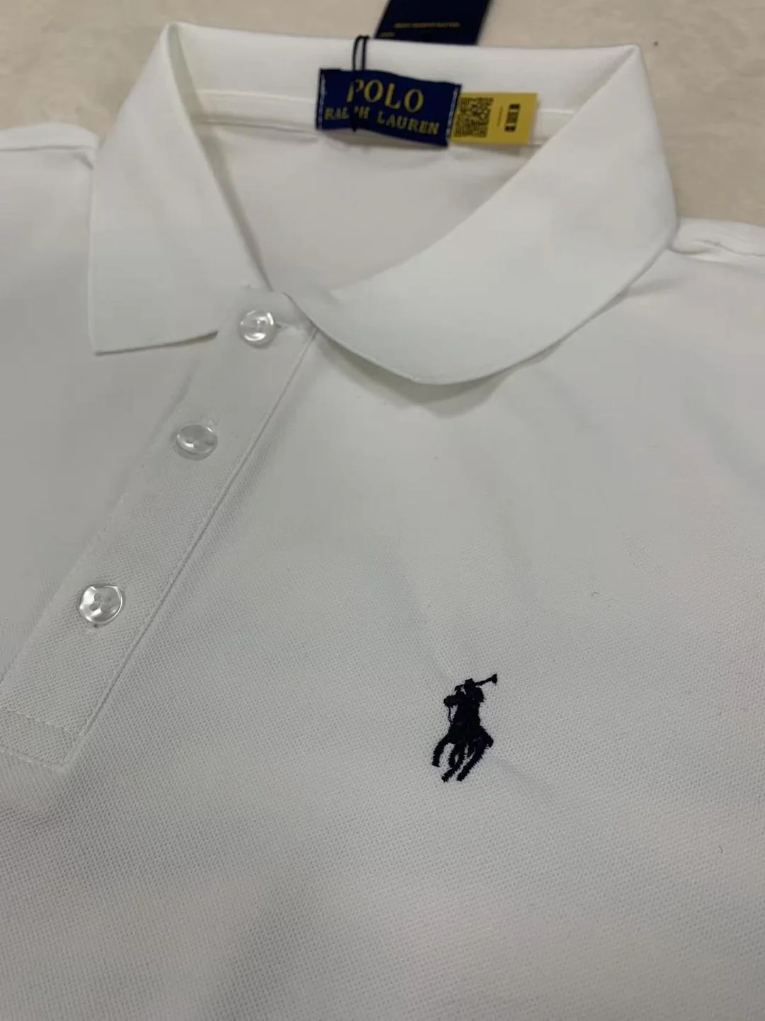 Close view of the white polo collar, buttons and embroidery